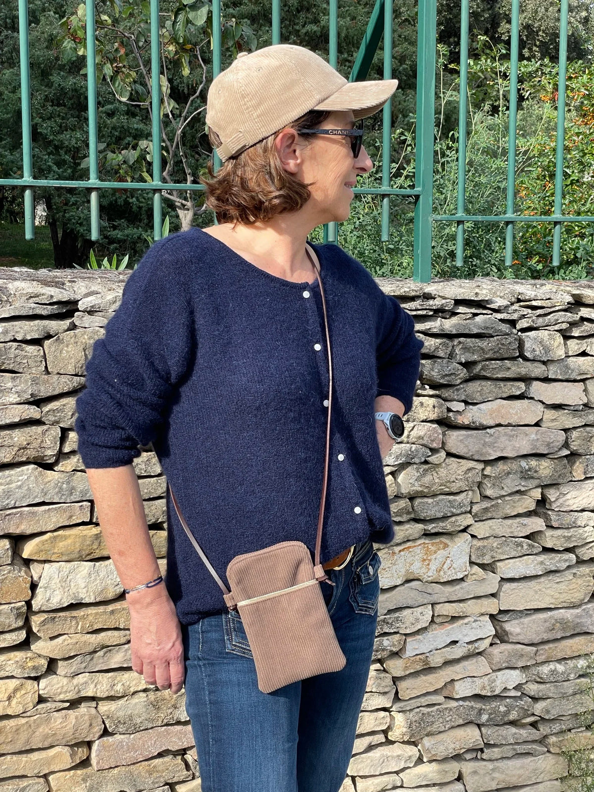 La pochette téléphone bandoulière en velours cotelé et cuir, portée en travers.