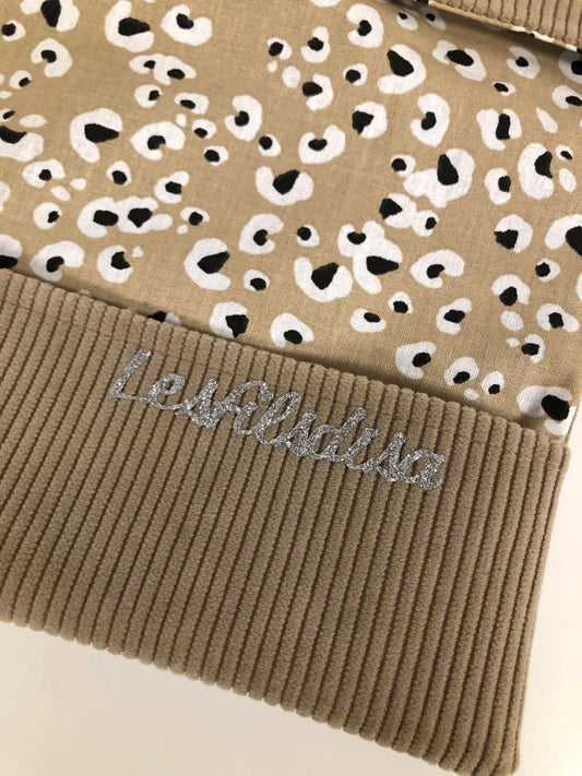 Le rabat inférieur du porte chéquier en velours tricoté beige avec étoile pailletée argentée.