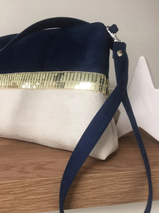 La bandoulière amovible du sac bandoulière Isa bleu marine et ivoire à paillettes dorées.