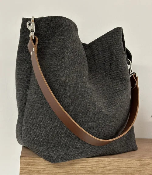 Le sac Hobo en lin anthracite et son anse en cuir marron, amovible.