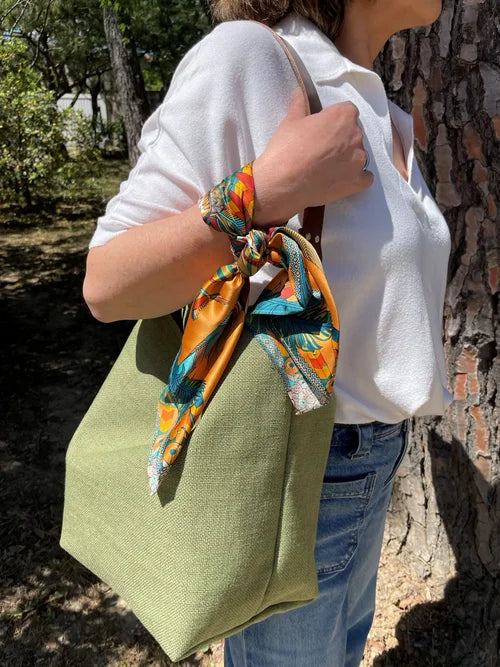 le sac hobo en lin vert kaki et son anse en cuir marron amovible, porté à l'épaule