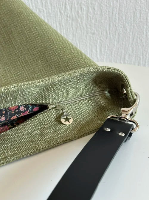La fermeture éclair du sac hobo en lin vert kaki et son anse en cuir noir amovible