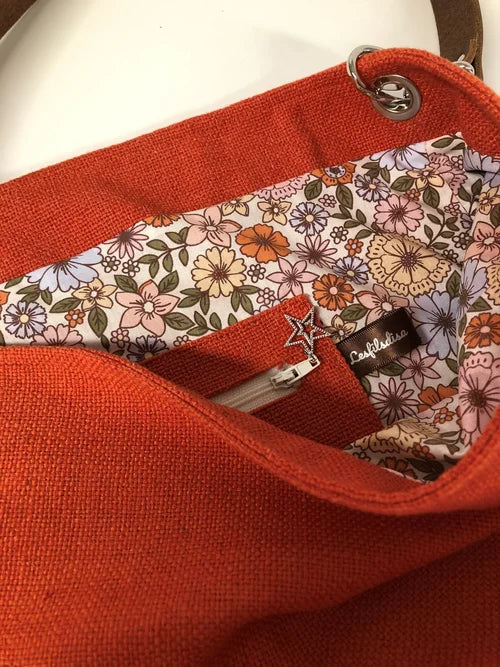 La poche intérieure zippée du sac Hobo en lin orangé et son anse en cuir marron amovible