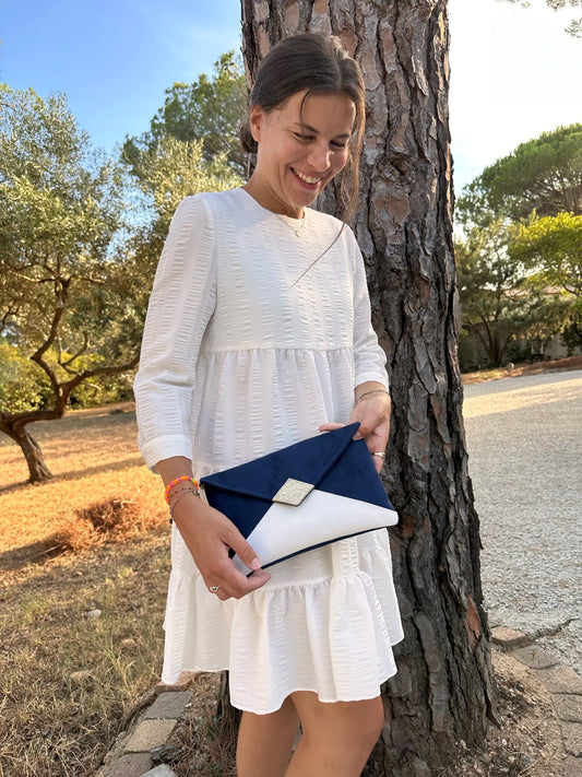 Jeune femme qui porte le sac pochette Isa bleu marine et blanc à paillettes dorées.