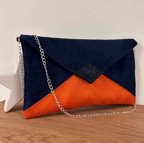 Le sac pochette Isa bleu marine et orange à paillettes, avec chainette argentée.