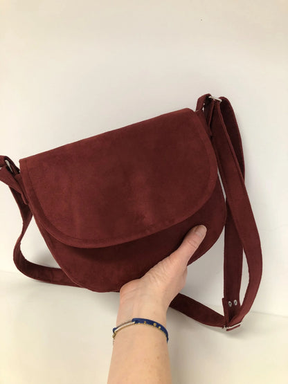 La besace Isa bordeaux, tenue en main.