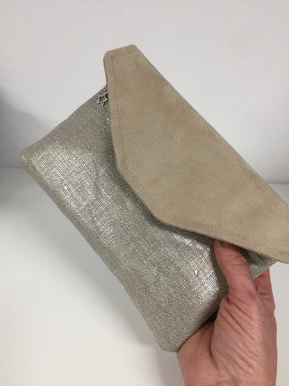Le compagnon de sac beige en lin argenté, tenu en main.