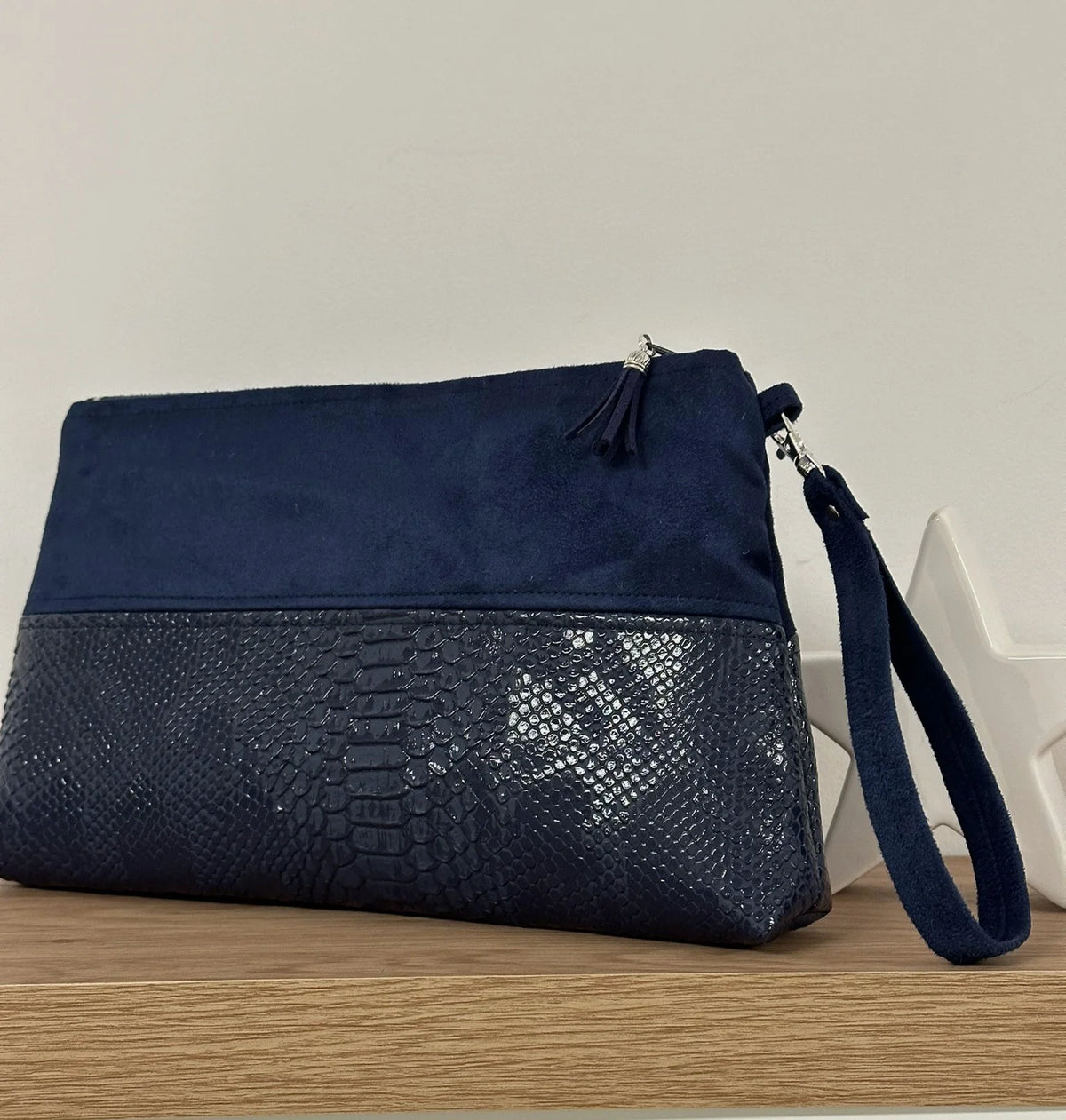 La pochette Isa zippée bleu marine aspect reptile, avec sa dragonne amovible.