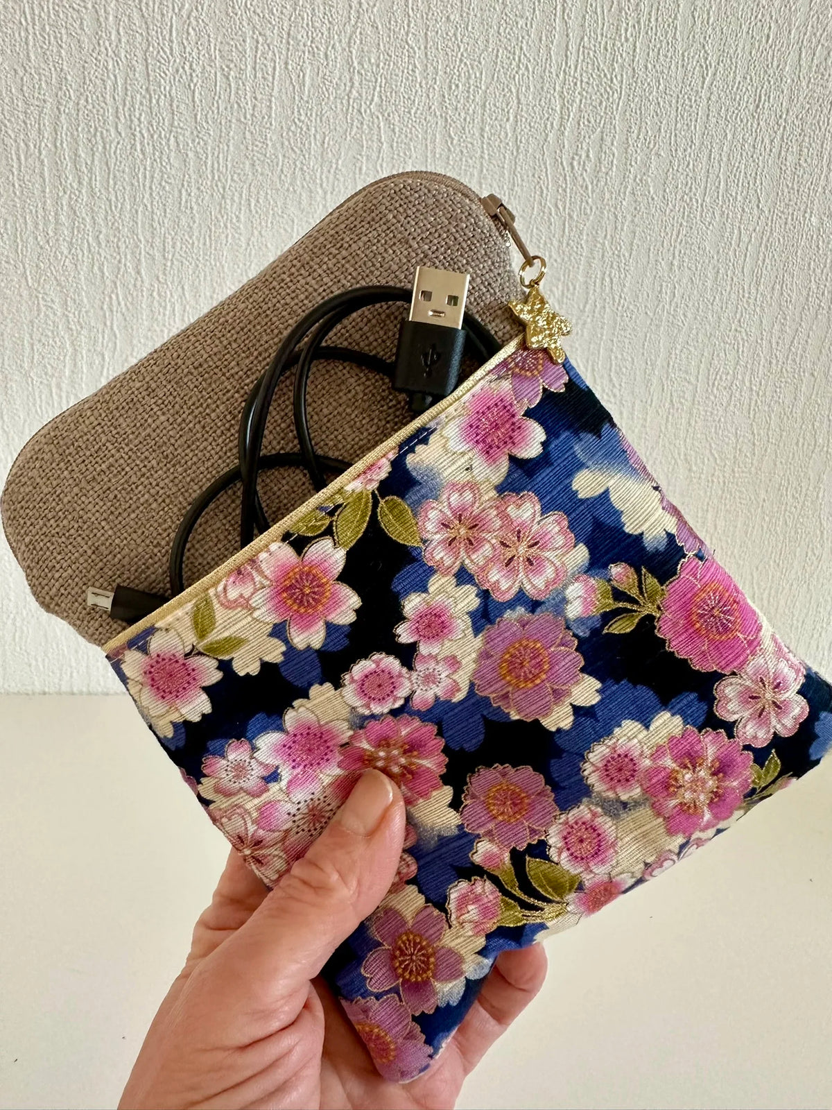 La pochette liseuse en lin et tissu japonais clématites tenue dans la main.