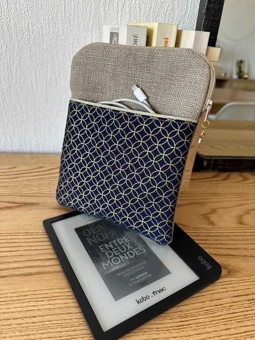 La pochette liseuse en lin et tissu japonais fleur de vie, format 7 pouces, avec Kobo Libra et câble de chargement dans la poche avant.