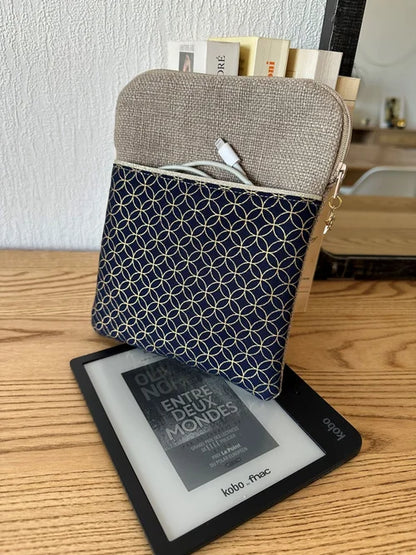 La pochette liseuse en lin et tissu japonais fleur de vie, format 7 pouces, avec Kobo Libra et câble de chargement dans la poche avant.