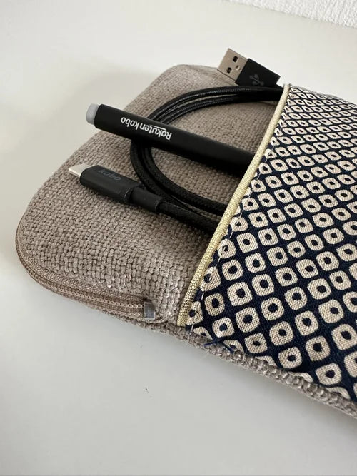 La poche avant de La pochette liseuse en lin et tissu japonais bleu Shibori, contenant stylet et cable de recharge.