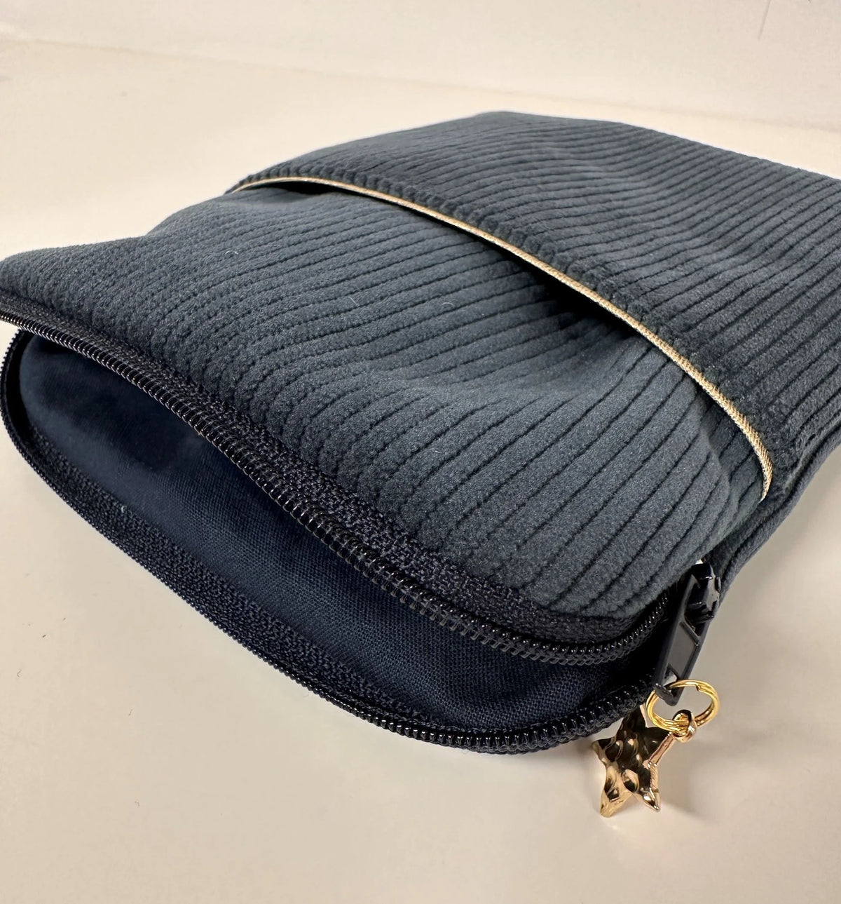 L'ouverture élargie de la pochette liseuse en velours cotelé bleu canard.