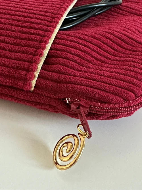La fermeture zippée de la pochette liseuse en velours cotelé bordeaux.
