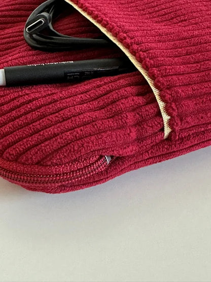 L'ouverture élargie de la pochette liseuse en velours cotelé bordeaux, avec stylet et cable dans la poche avant.