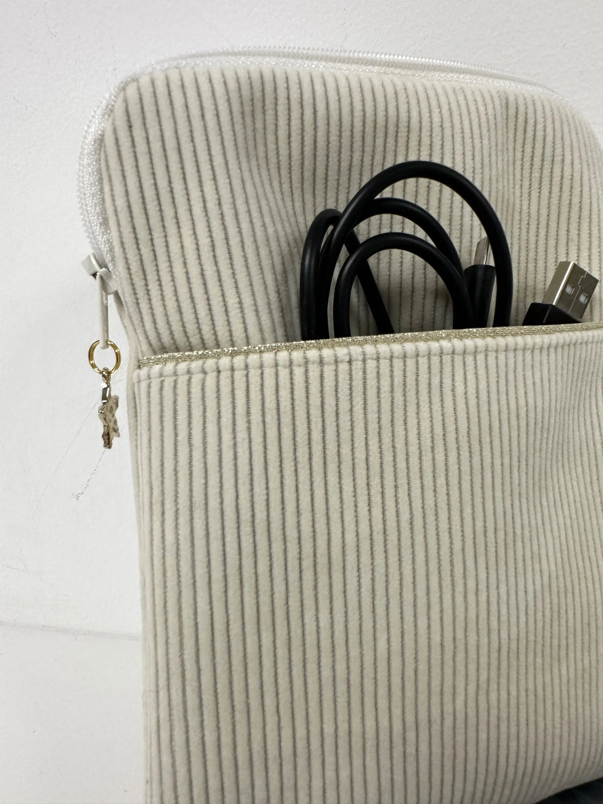 La poche avant de la pochette à liseuse en velours cotelé écru.