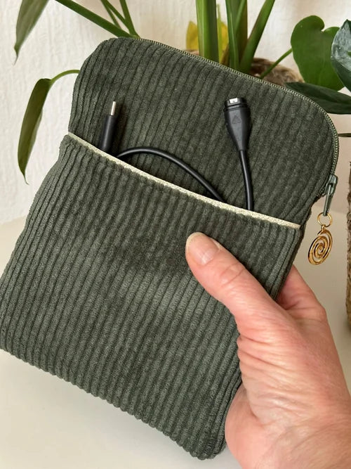 La pochette liseuse en velours cotelé vert kaki, format 6 pouces, tenue en main.
