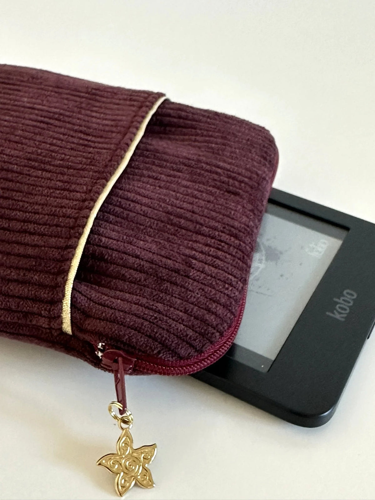 La fermeture zippée de la pochette liseuse en velours prune.