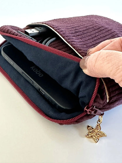 L'ouverture élargie de la pochette liseuse en velours prune.
