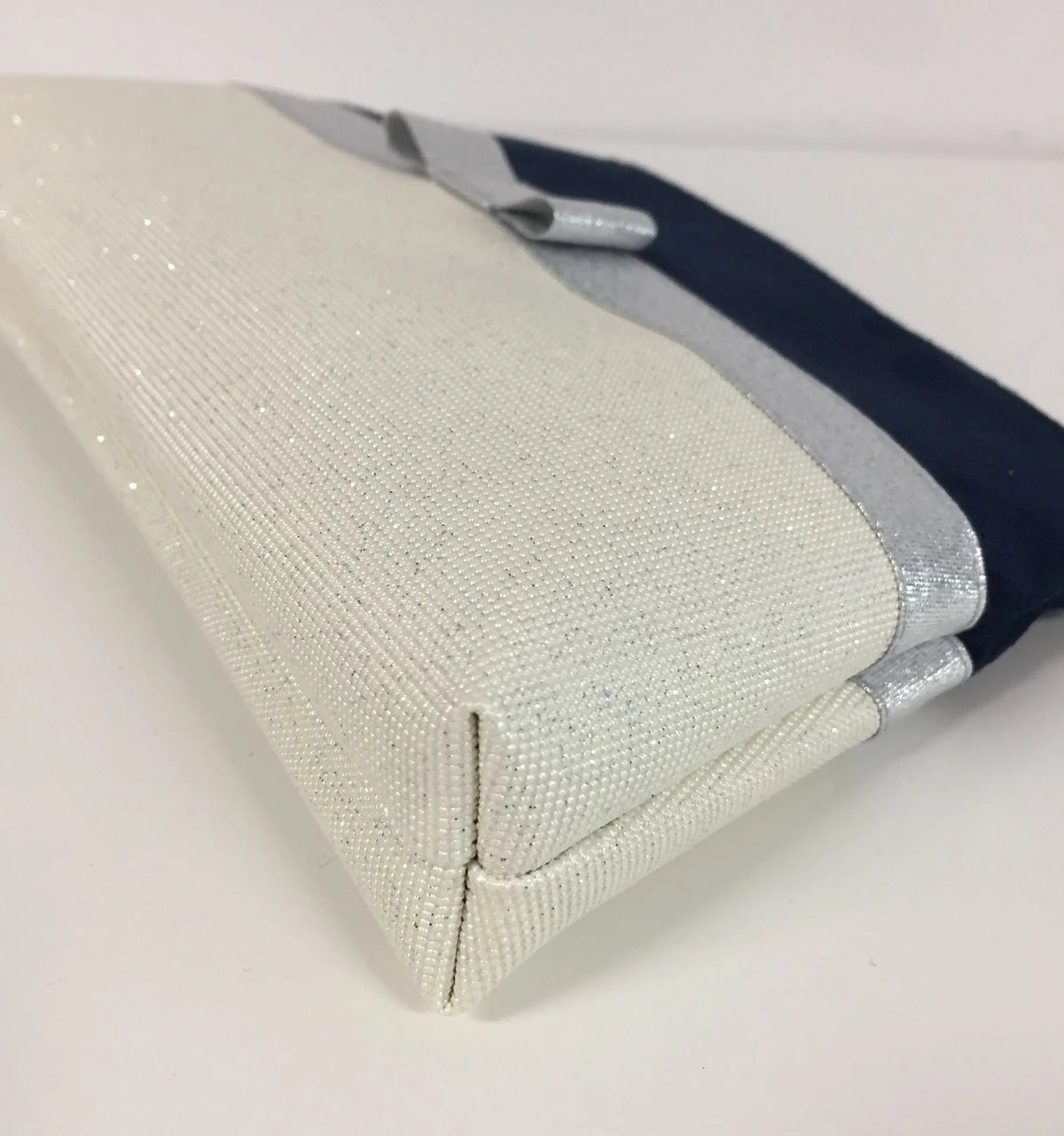 Le fond de la pochette à maquillage bleu marine et blanc à noeud argenté.