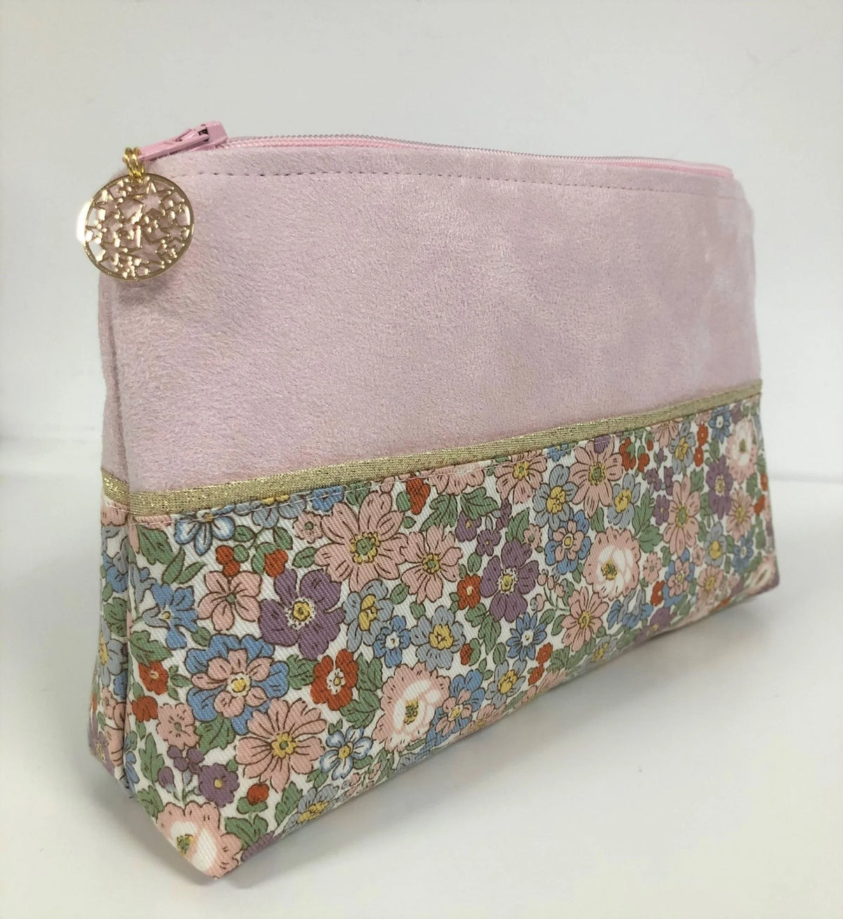 Vue latérale de la pochette à maquillage rose et dorée à fleurs pastel.