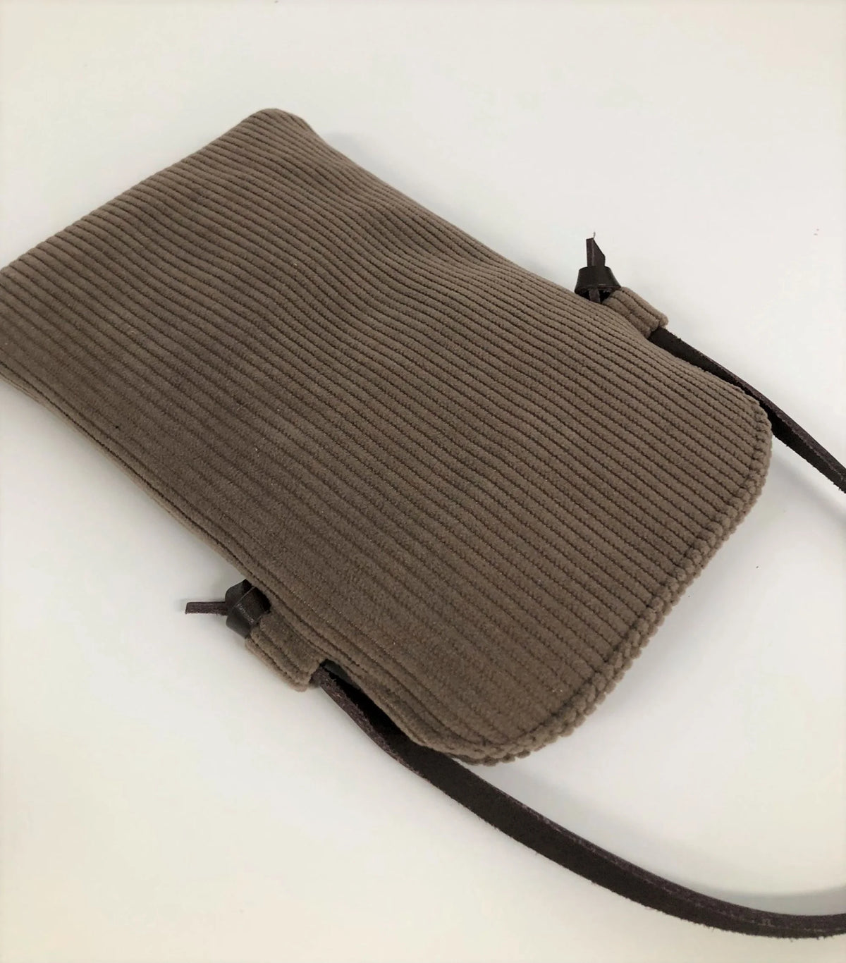 Le dos de la pochette téléphone bandoulière en velours cotelé marron chamois et cuir.