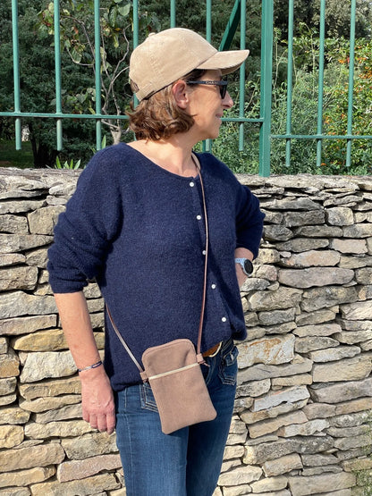 La pochette téléphone bandoulière en velours cotelé et cuir, portée en travers.
