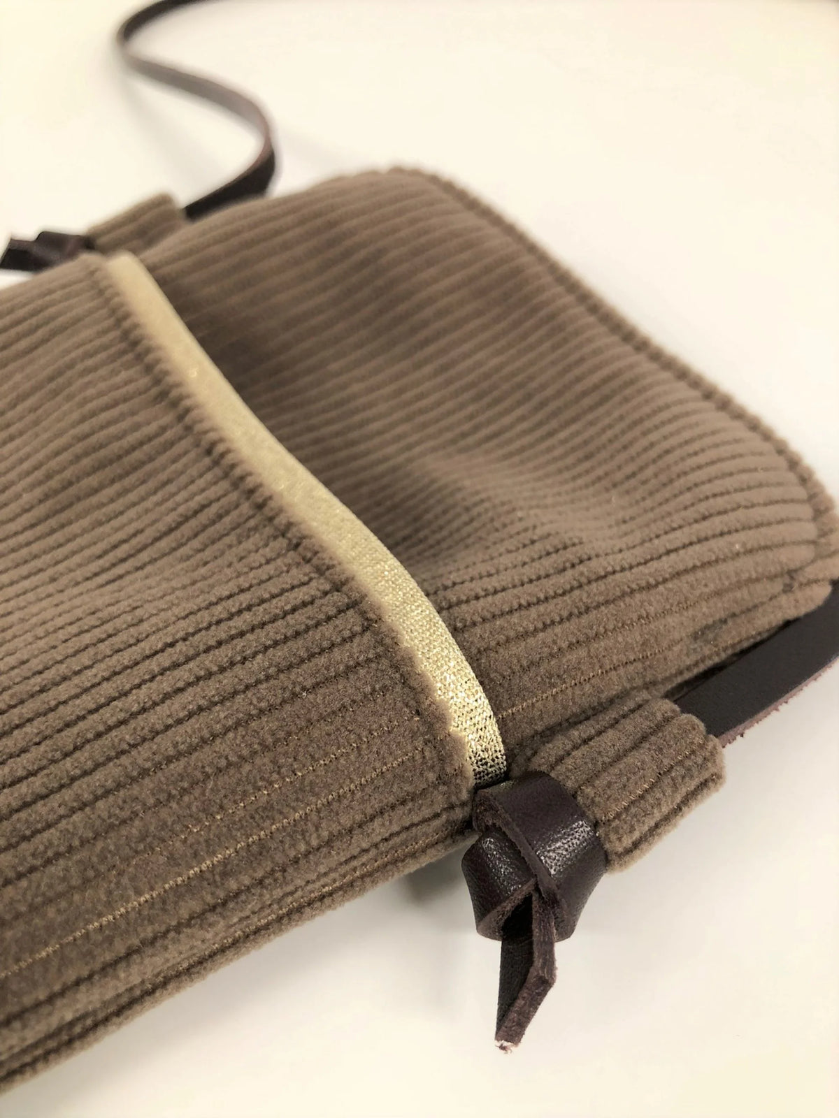 La poche avant de la pochette téléphone bandoulière en velours cotelé marron chamois et cuir .