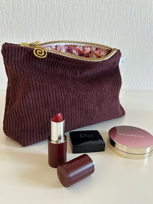La pochette en velours côtelé prune, ouverte.