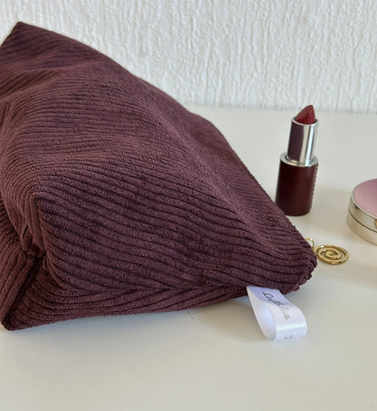 Vue latérale de la pochette en velours côtelé prune.