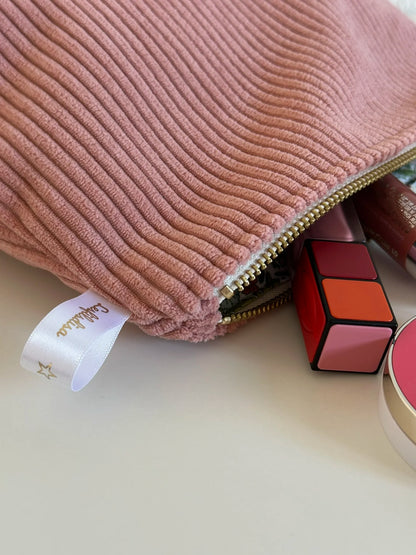 La fermeture éclair dorée de pochette en velours côtelé rose blush.
