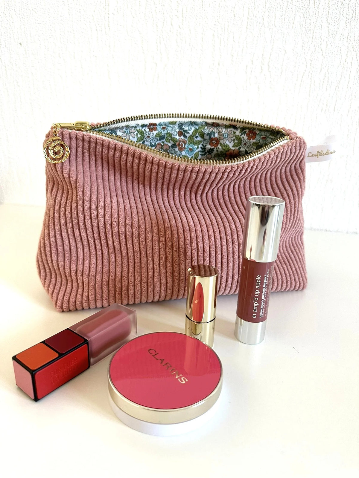 La pochette en velours côtelé rose blush, entrouverte.