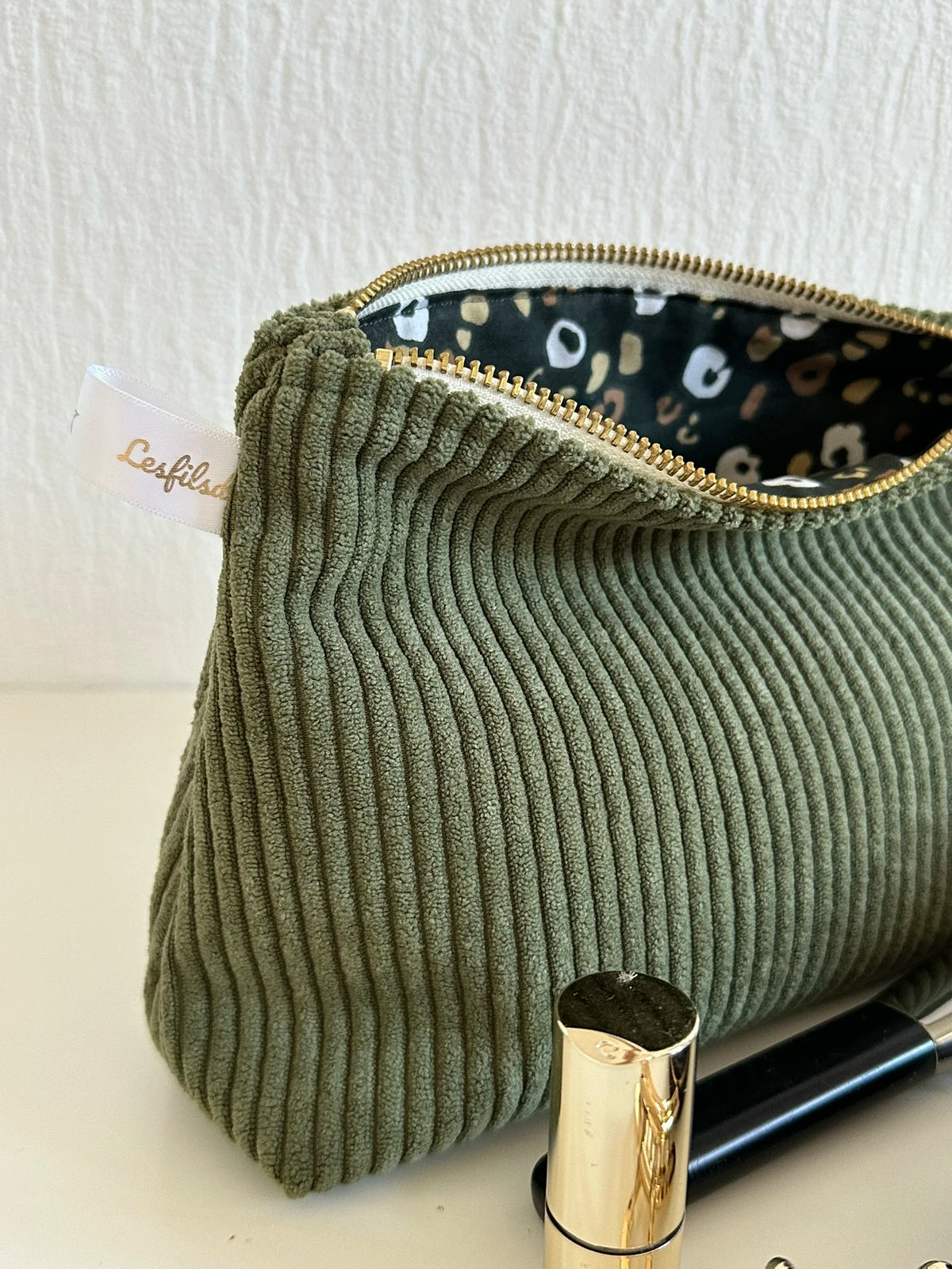 La fermeture métal doré de la pochette en velours côtelé vert armée.