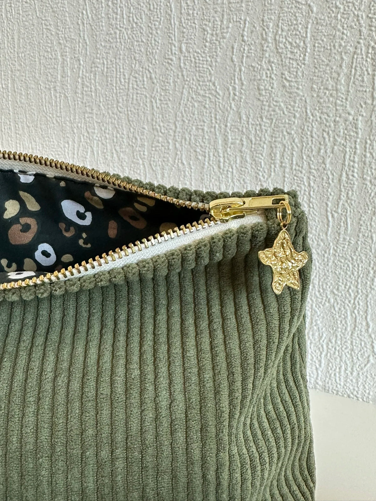 La breloque dorée de la pochette en velours côtelé vert armée.