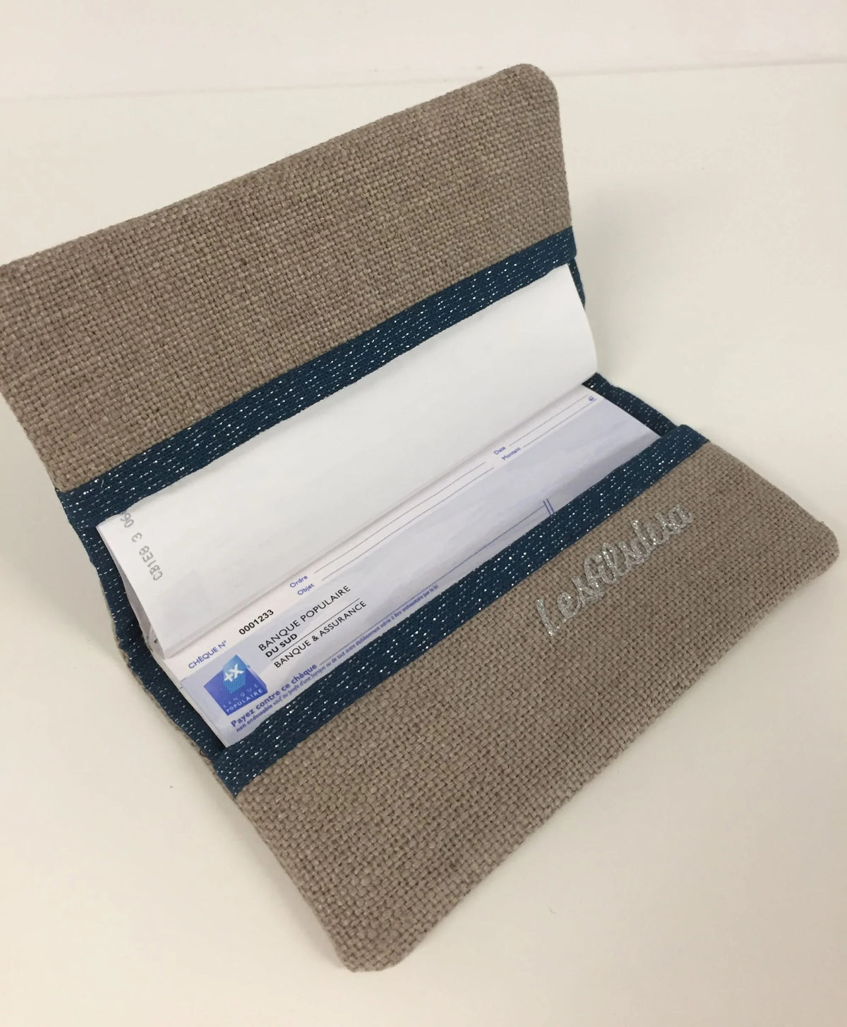 Vue intérieure du porte-chéquier beige et bleu marine pailleté à liseré argenté.