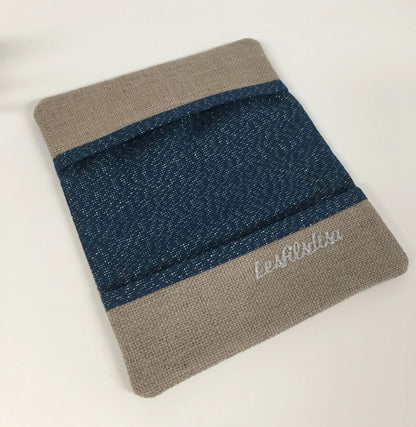 Le porte-chéquier beige et bleu marine pailleté à liseré argenté, ouvert et vide. 