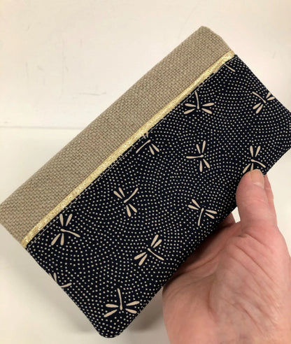 Le porte chéquier en lin beige et tissu japonais bleu libellules, tenu en main.
