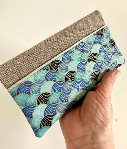 Le porte chéquier en lin et tissu japonais bleu turquoise, tenu en main.