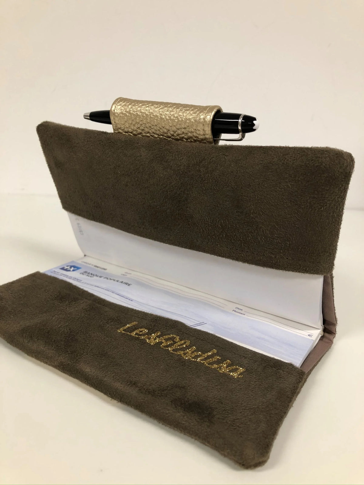 Le porte-chéquier marron et doré avec porte-stylo, ouvert.