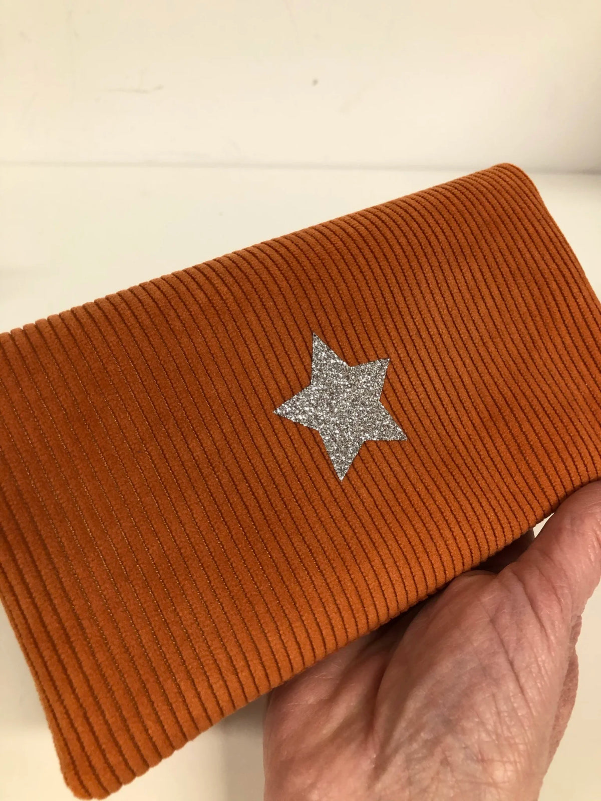 La face avant du porte chéquier en velours côtelé orange et son étoile pailletée argentée 