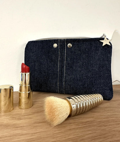 Le porte-monnaie en denim brut, avec ses surpiqures et rivets métalliques.