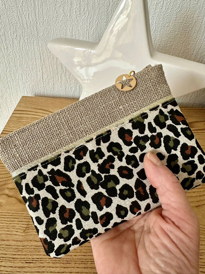 Le porte monnaie léopard en lin beige, tenu en main.