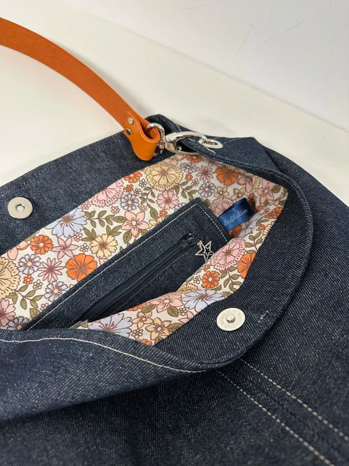 La poche intérieure zippée du sac hobo en denim et son anse en cuir orange 