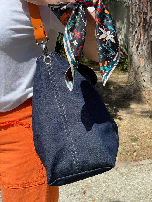 Les surpiqures du sac hobo en denim et son anse en cuir orange 