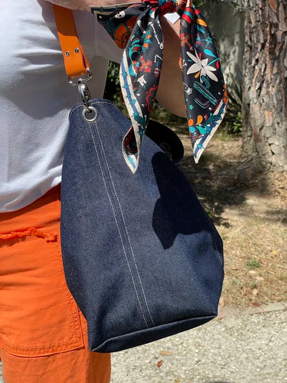 Les surpiqures du sac hobo en denim et son anse en cuir orange 