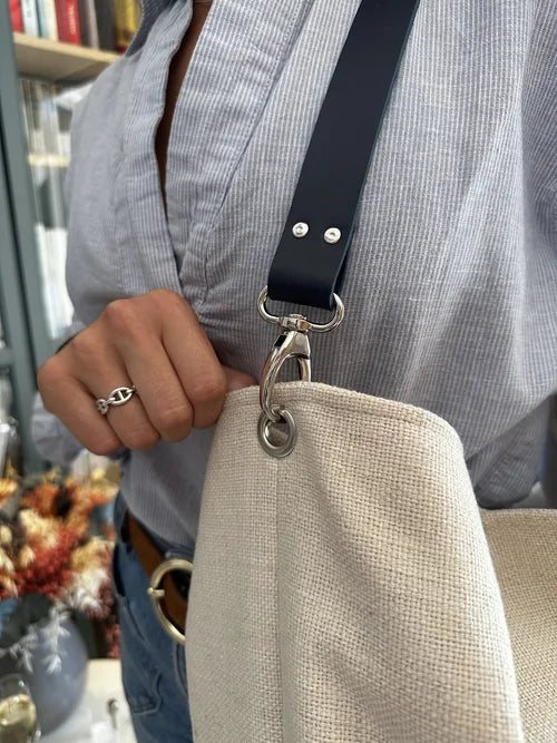 L'anse en cuir du sac Hobo en lin ivoire et anse amovible en cuir bleu.