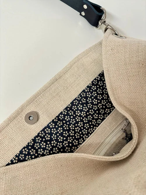 La poche zippée intérieure du sac Hobo en lin ivoire et anse amovible en cuir bleu.