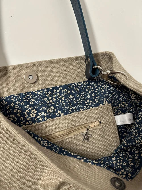 La poche  zippée intérieure du sac Hobo en lin beige et son anse en cuir bleu marine 