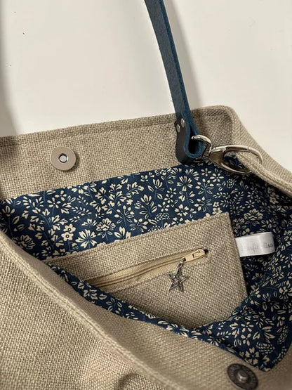 La poche  zippée intérieure du sac Hobo en lin beige et son anse en cuir bleu marine 