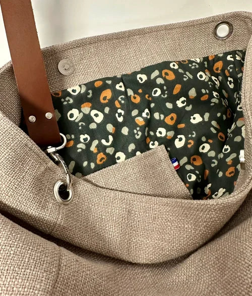 La doublure intérieure avec la poche plaquée du sac hobo en lin beige et anse en cuir amovible.
